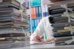 © stokkete / stock.adobe.com Mann arbeitet hinter Aktenstapel